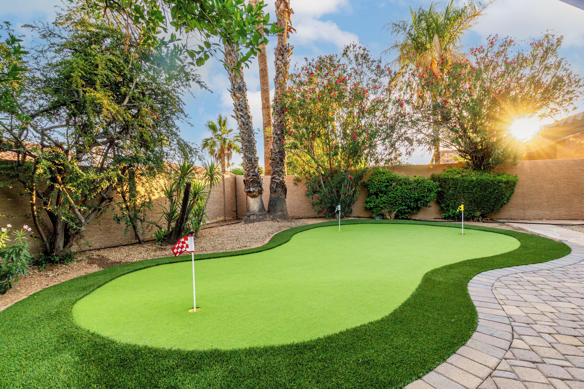 Ein gepflegter Golfplatz mit Putting Green, umgeben von üppiger Vegetation und Palmen.