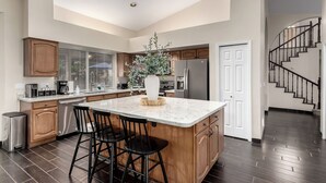 A modern kitchen with a large island, wooden cabinets, and a stainless steel refrigerator. - Spanish Wells Scottsdale Oasis (Scottsdale)