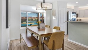 Eine moderne Küche mit weißen Schränken, einem Edelstahlkühlschrank und einem Holzespeisetisch mit Stühlen.