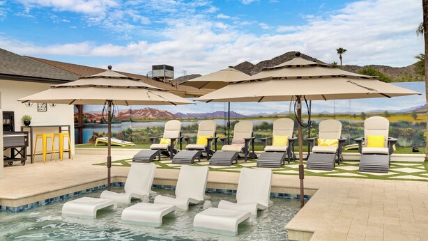 Ein Poolbereich mit Liegestühlen und Sonnenschirmen, einem Pool und einem Wandbild mit Landschaftsmotiv.