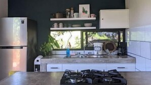 Une cuisine moderne équipée d’une cuisinière à gaz, de meubles blancs et d’une fenêtre donnant sur un paysage verdoyant.