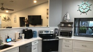A modern kitchen with a dishwasher, stove, oven, microwave, and a large window. - Charming remodeled waterfront home in marco island. (Marco Island)