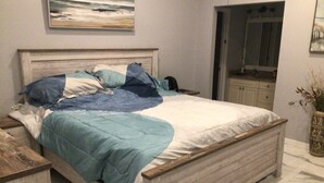 A bedroom with a wooden bed, a nightstand, a dresser, and a mirror. - Charming remodeled waterfront home in marco island. (Marco Island)