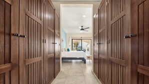 Un pasillo con puertas de madera que dan a un dormitorio con cama y ventilador de techo.