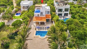 Una villa moderna con piscina, rodeada de abundante vegetación y palmeras.