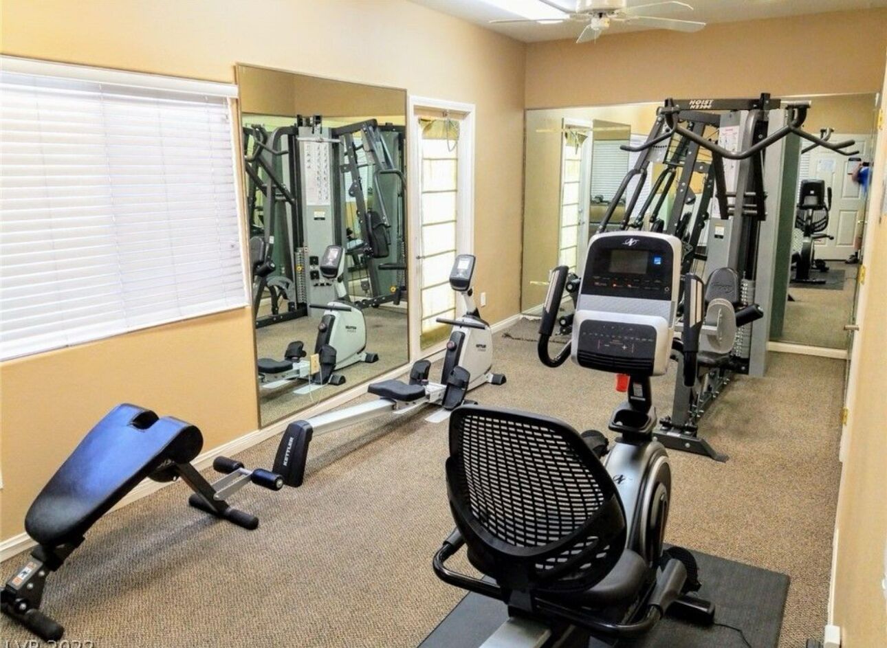 A gym with exercise equipment, a bench, and a mirrored wall.