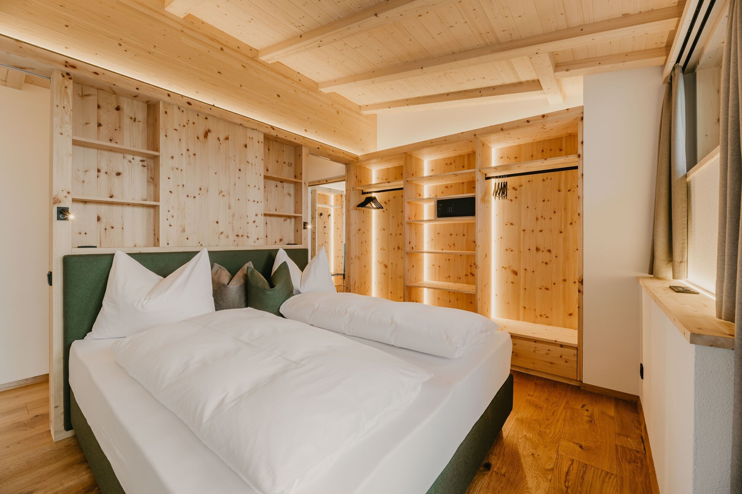 A wooden-paneled bedroom with a bed, built-in shelving, and a walk-in closet.