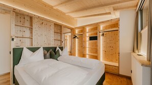 Een slaapkamer met houten lambrisering, een bed, inbouwkasten en een inloopkast.