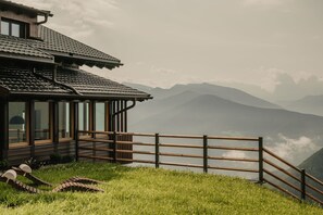 A wooden building with large windows, a wooden fence, and a grassy area. - Apartment 'Gipfeltraum' with Mountain View, Shared Garden and Wi-Fi (Chiusa)