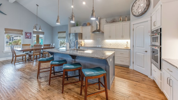 A modern kitchen with a large island, pendant lights, and white cabinetry. - 4/4. Pool & Golf Cart.  1st Floor Master Suite.  2 Masters Up, Boat Parking.  
 (Port Aransas)
