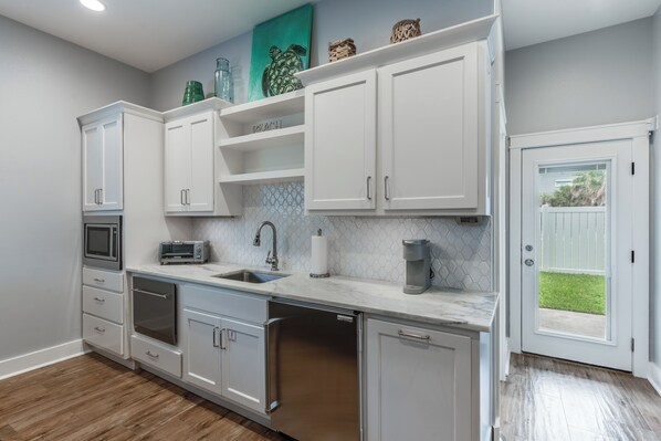 A modern kitchen with white cabinets, a built-in dishwasher, a microwave, and a coffee maker. - 4/4. Pool & Golf Cart. 1st Floor Master Suite. 2 Masters Up, Boat Parking.
(Port Aransas)
