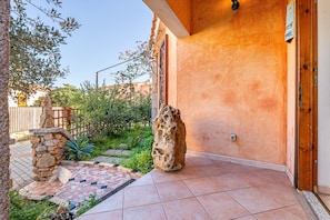Un pilier de pierre, une terrasse carrelée et une porte en bois.