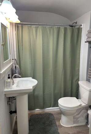 Une salle de bain avec un lavabo blanc, des toilettes et un rideau de douche vert.