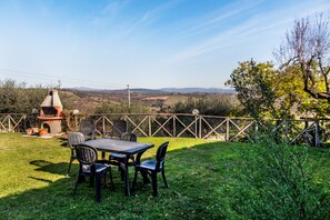 A patio with a table and chairs, a chimney, and a view of hills.