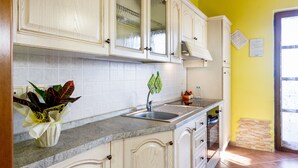 Cozinha com armários brancos, bancada de granito, pia e janela com vista.