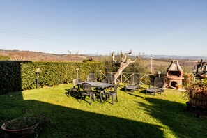 Um pátio com mesa e cadeiras, churrasqueira e vista para o campo.