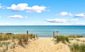 A sandy beach with a wooden fence and a signpost, leading to the ocean. - Bright & Beautiful - Family-Friendly, Newly Renovated, Steps to the Shore! (Spring Lake)