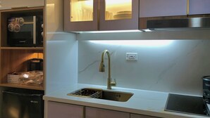 A modern kitchen with a stainless steel sink, a built-in oven, and a coffee machine. - Cozy Retreat 1-bedroom unit with pool and balcony in Mall of Asia (MOA) (Pasay)