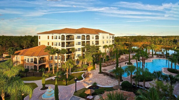A resort with a large building, a swimming pool, and palm trees.
