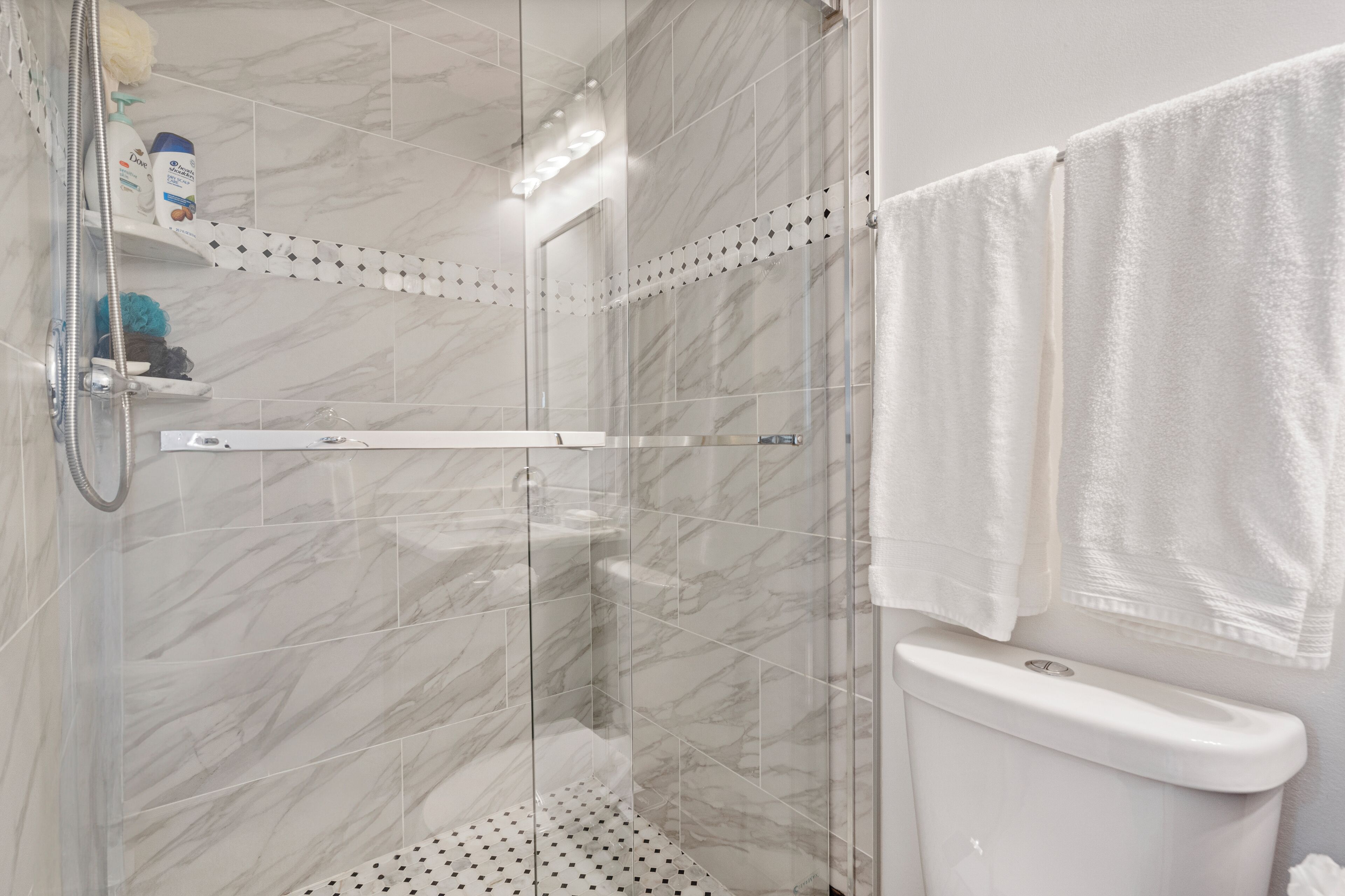 Ein modernes Badezimmer mit einer Duschkabine, einer Toilette und einem Ablagefach mit Pflegeprodukten.
