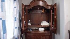 A wooden wardrobe with a mirror, a hanging rack, and a shelf with folded towels and a kettle. - National Harbor Property 1 (Fort Washington)
