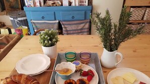 A dining table with plates of food, a tray with drinks, and a croissant. - Apartment 'Casa De Mondo - Blue Room' with Shared Pool, Wi-Fi and Air Conditioning (Boliqueime)