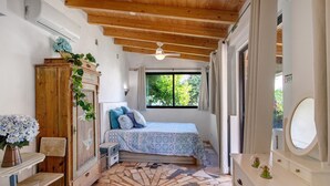 A bedroom with a bed, dresser, vanity, and a window with a view of greenery. - Apartment 'Casa De Mondo - Blue Room' with Shared Pool, Wi-Fi and Air Conditioning (Boliqueime)
