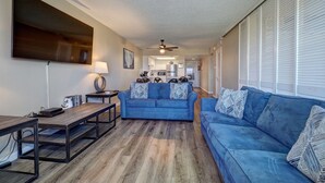 Un salon avec un canapé bleu, une table basse et un téléviseur fixé au mur.