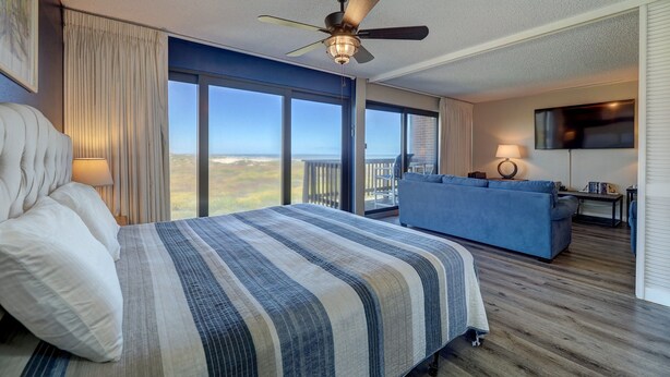Une chambre d’hôtel avec un grand lit, un ventilateur de plafond, une télévision et un balcon avec vue.