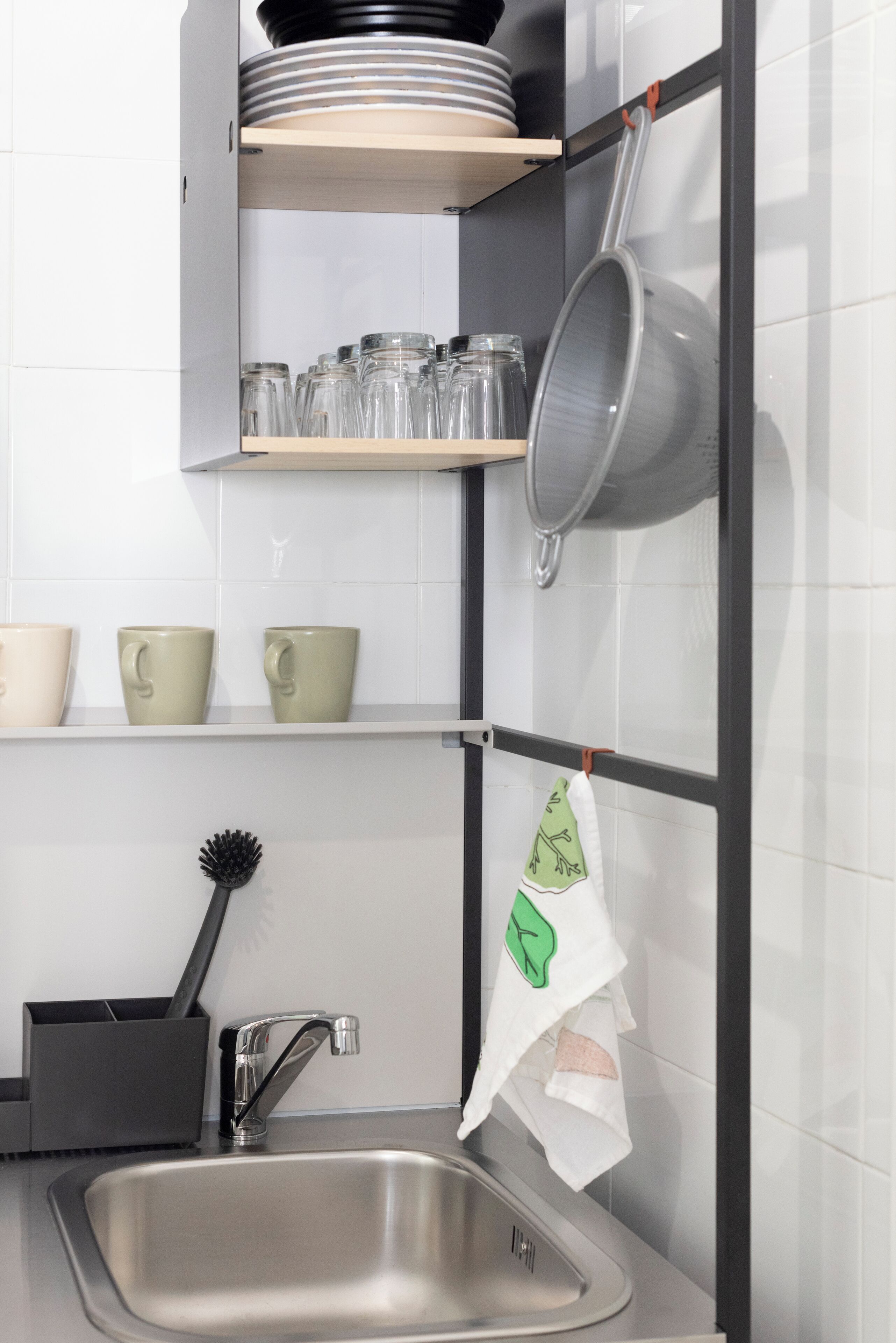 Una cocina con un lavamanos de acero inoxidable, un escurreplatos y un colgador para ollas.