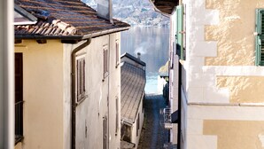 Une rue étroite bordée de bâtiments des deux côtés, une vue dégagée sur une étendue d’eau et une vue lointaine sur une chaîne de montagnes.