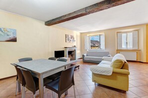 Un salon comprenant une table à manger, un canapé, une cheminée et de grandes fenêtres.
