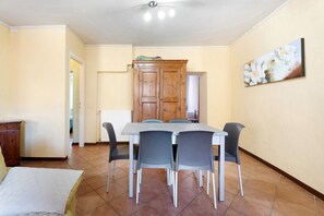 A dining area with a table and chairs, a wooden cabinet, and a painting on the wall. - ‘Cabianchi Royal Suite’ Apartment with Lake View, Balcony and Wi-Fi (Orta San Giulio)