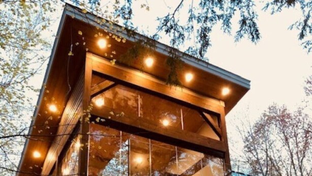 Een houten chalet met grote ramen en een balkon, omgeven door bomen.