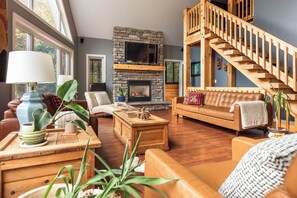 A cozy living room with a stone fireplace, wooden staircase, and comfortable seating. - Camp David Beautiful five bedrooms  Private beach (Kearney)