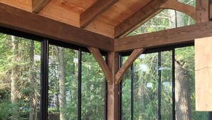 Eine Holzhütte mit einem großen Fenster, einem Deckenventilator und einer Sitzecke mit Kissen.