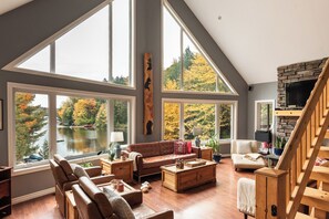 A spacious living room with large windows, a fireplace, and a view of a lake. - Camp David Beautiful five bedrooms  Private beach (Kearney)