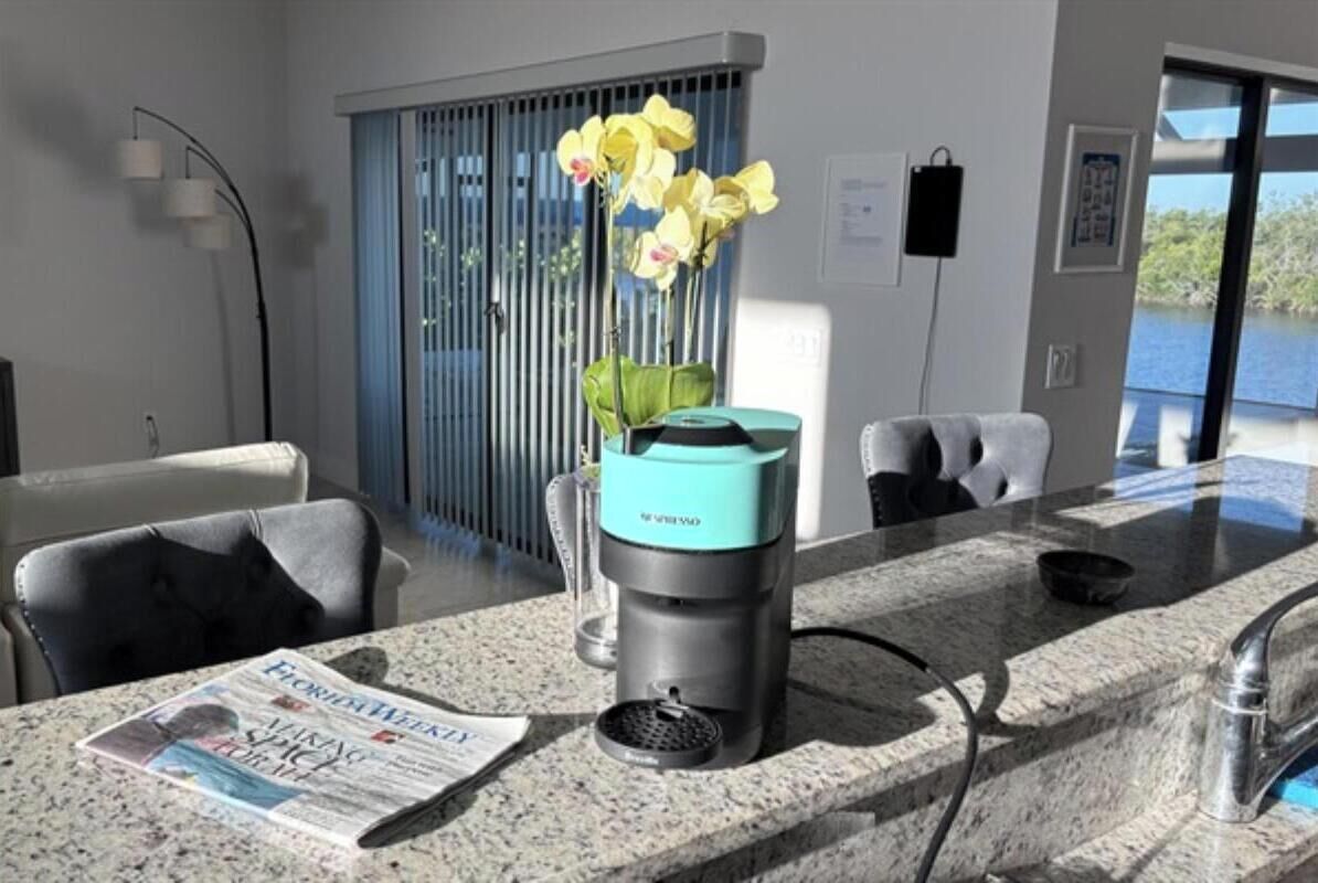 A modern kitchen with a granite countertop, a coffee maker, and a newspaper.