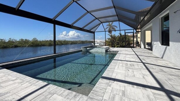 An infinity pool with a clear view of the water and palm trees, surrounded by a covered patio area.