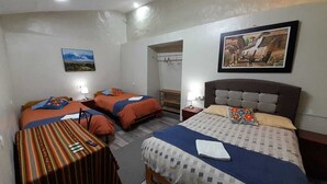 A hotel room with two single beds, a large bed, a small table, and a mirror. - We are located in the Historic Center of Cusco, behind the Cathedral, Plaza Mayor. (Cusco)