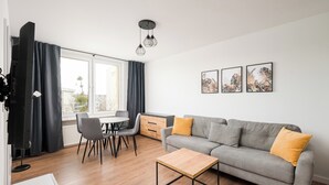 Una sala moderna con un sofá gris, una mesa de centro de madera y un comedor con sillas y una mesa.