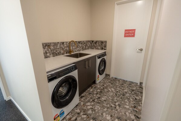 A laundry room with a washing machine, dryer, and sink. - Serenity Hideaway House A (Twizel)