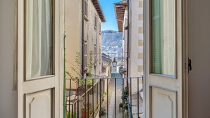 Puerta abierta que da a un estrecho callejón, con vistas a edificios y una montaña distante.