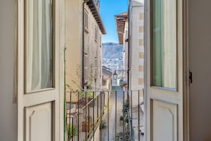 Puerta abierta que da a un estrecho callejón, con vistas a edificios y una montaña distante.