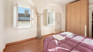 Un dormitorio con cama, armario de madera y ventana con persiana abierta.