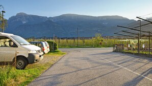Un estacionamiento con una fila de coches, una valla y montañas al fondo.