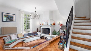 A living room with a sofa, TV, fireplace, and a staircase.