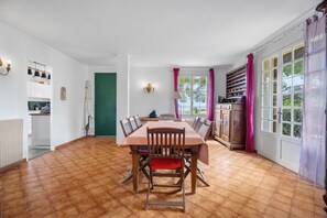 A dining area with a table and chairs, a kitchen area with cabinets and a window, and a green door.