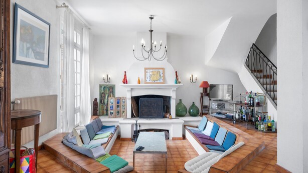 A spacious living room with a fireplace, seating area, and a staircase.