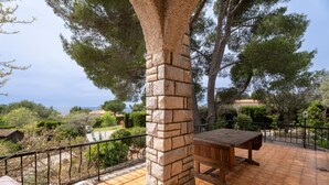 A patio with a stone pillar, a wooden table, and a bench.